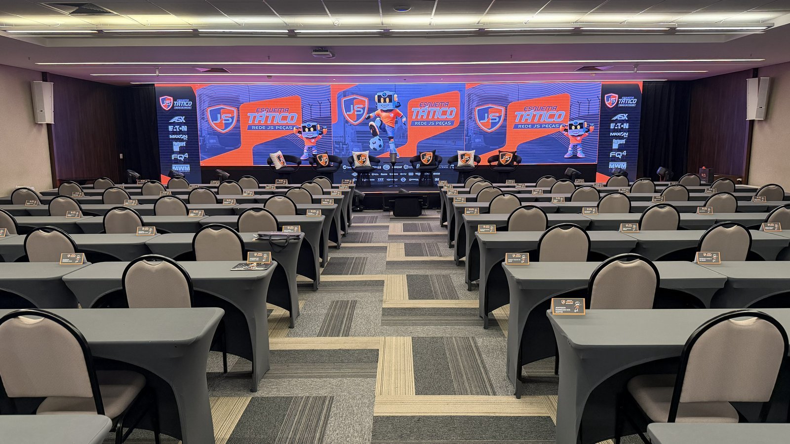 Convenção JS Peças — Salão principal com palco e telas LED